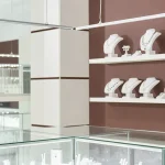 Jewelry store showroom with organized displays of necklaces and rings in glass display cases.