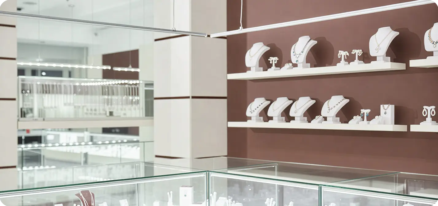 Jewelry store showroom with organized displays of necklaces and rings in glass display cases.