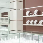 Jewelry store showroom with organized displays of necklaces and rings in glass display cases.